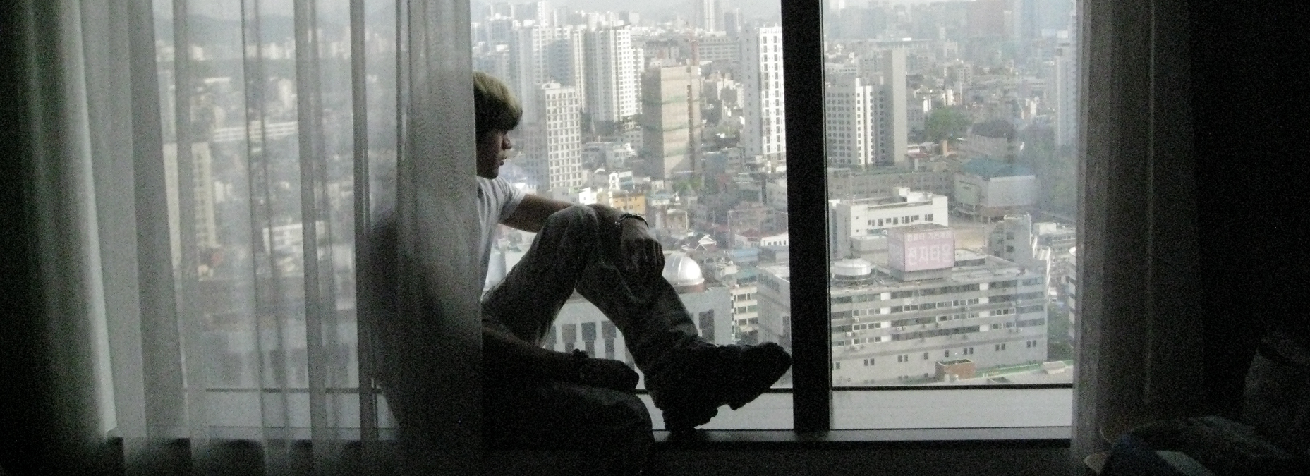 Person sitting by window overlooking city skyline